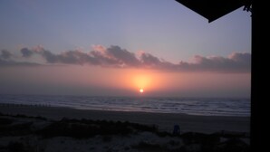 A sunset over the ocean with a beach in the foreground.