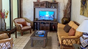 A cozy living room with a television, wicker furniture, and decorative items.