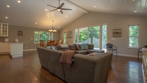 Ein geräumiges Wohnzimmer mit einer großen Eckcouch, einem Essbereich mit Holztisch und -stühlen sowie einer Küche mit weißen Schränken.
