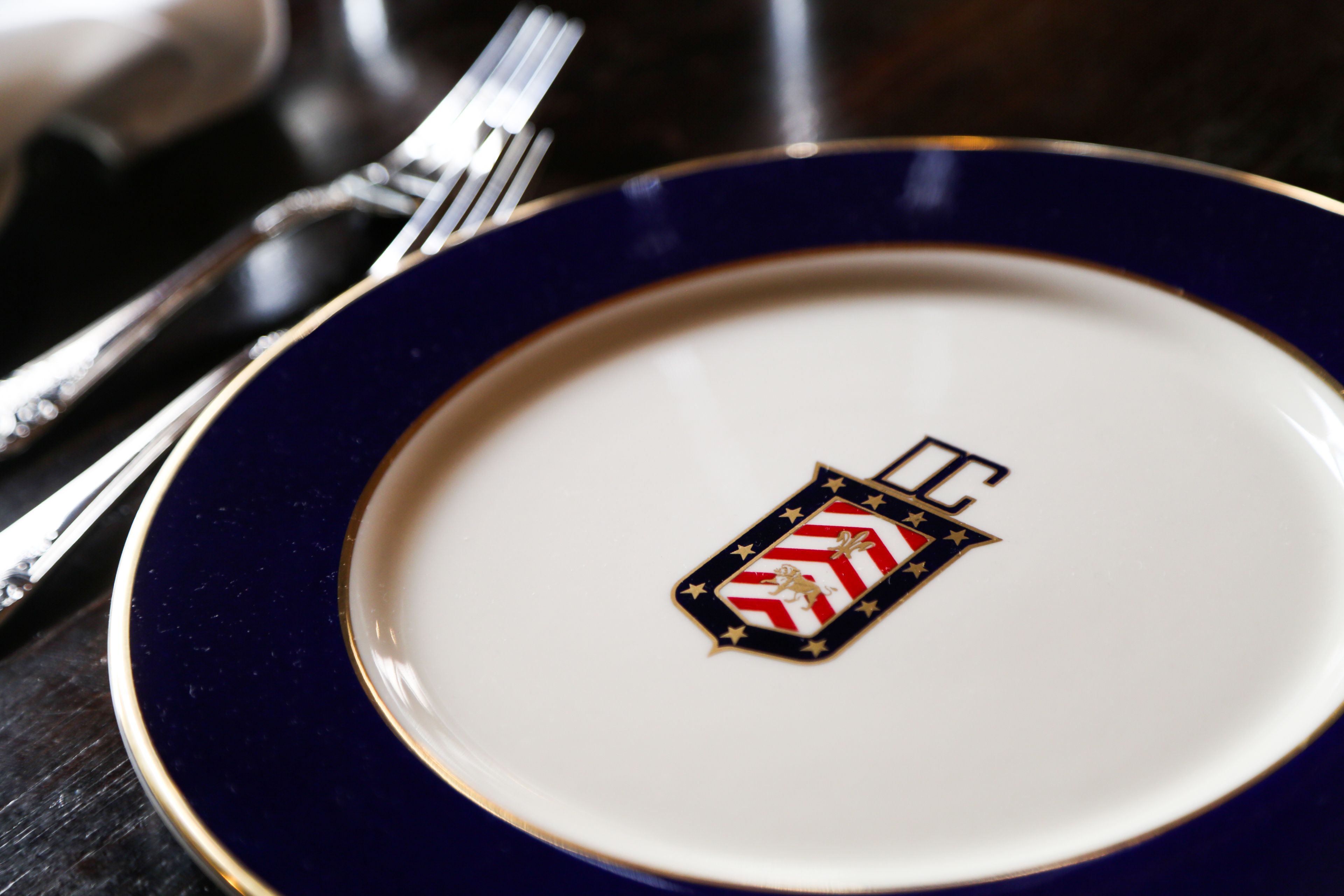 A close-up of a white plate with a blue rim and a decorative emblem.