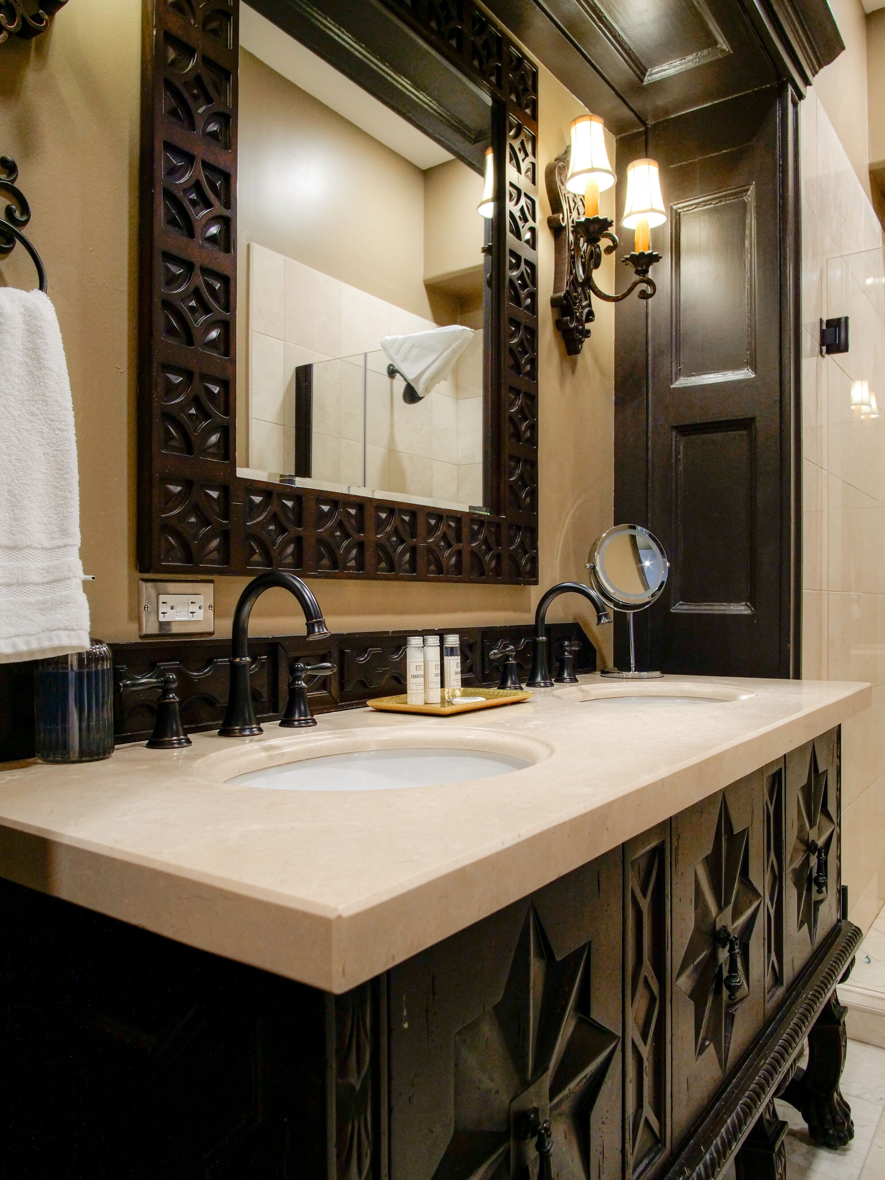 A bathroom with a large mirror, two sinks, and decorative wall sconces.