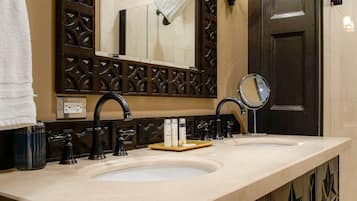 A bathroom with a large mirror, two sinks, and decorative wall sconces.