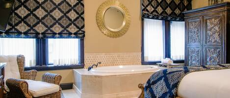 Un baño amplio con una bañera grande, un espejo y una silla de mimbre.