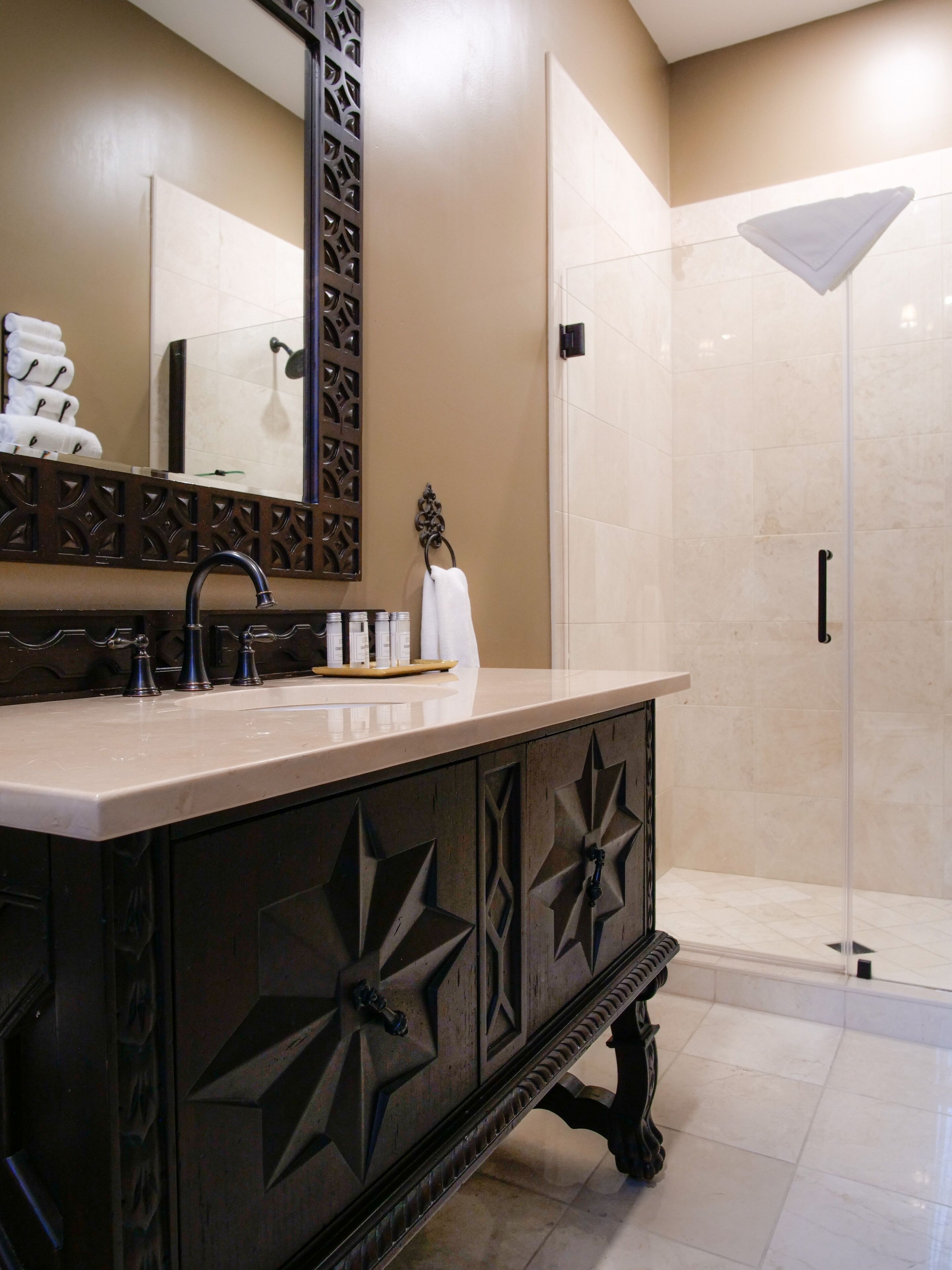 A modern bathroom with a large mirror, a sink with multiple faucets, and a shower area.