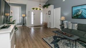 Un salon moderne avec un canapé vert, un tapis à motifs et un téléviseur à écran plat.