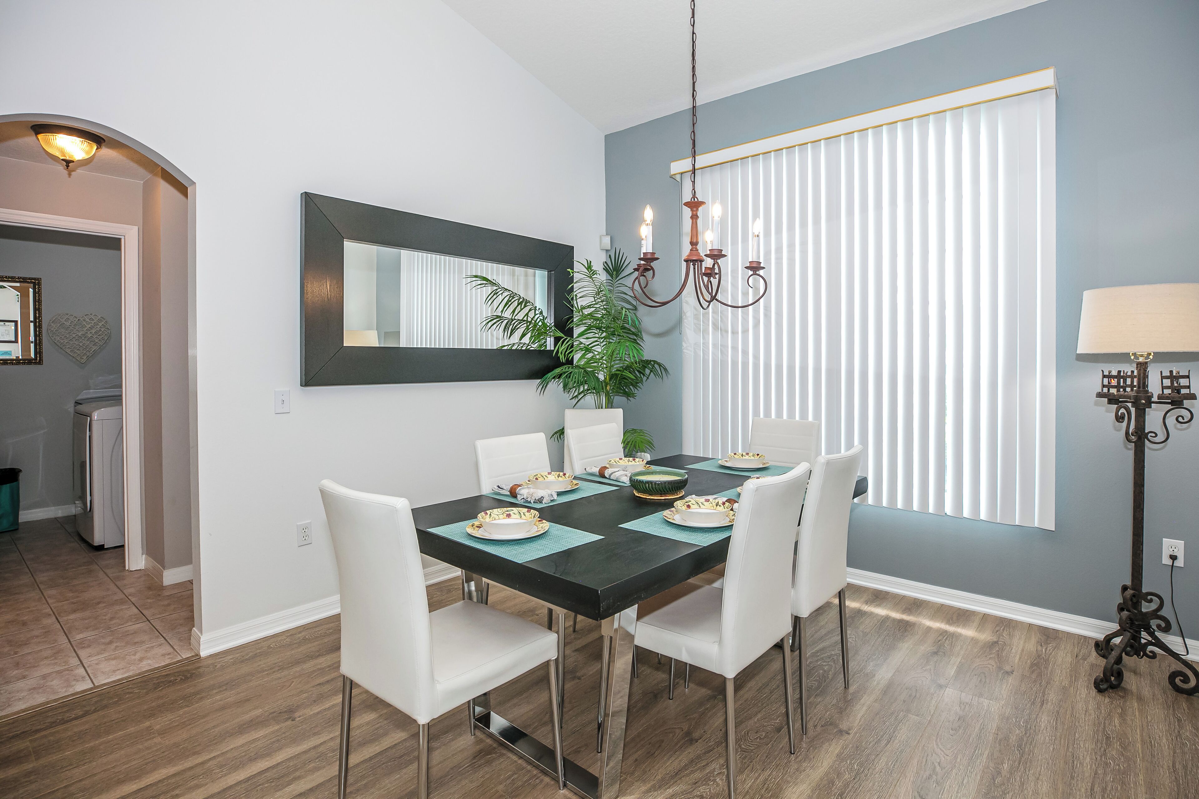 A dining area with a black table, white chairs, and a chandelier.
