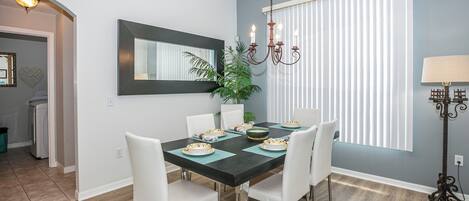 A dining area with a black table, white chairs, and a chandelier.