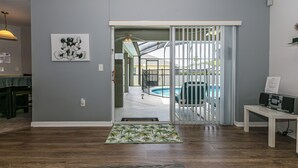 Un salon avec vue sur la piscine, un ventilateur de plafond et une porte donnant sur l’extérieur.