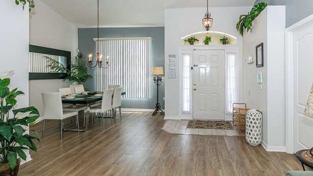 Un salon moderne avec un coin repas, doté d’un parquet, de meubles blancs et de plantes vertes.