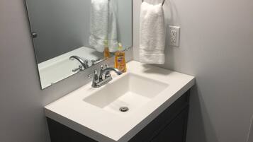 Une salle de bain avec un lavabo blanc, des meubles sombres, un miroir et une serviette accrochée au mur.