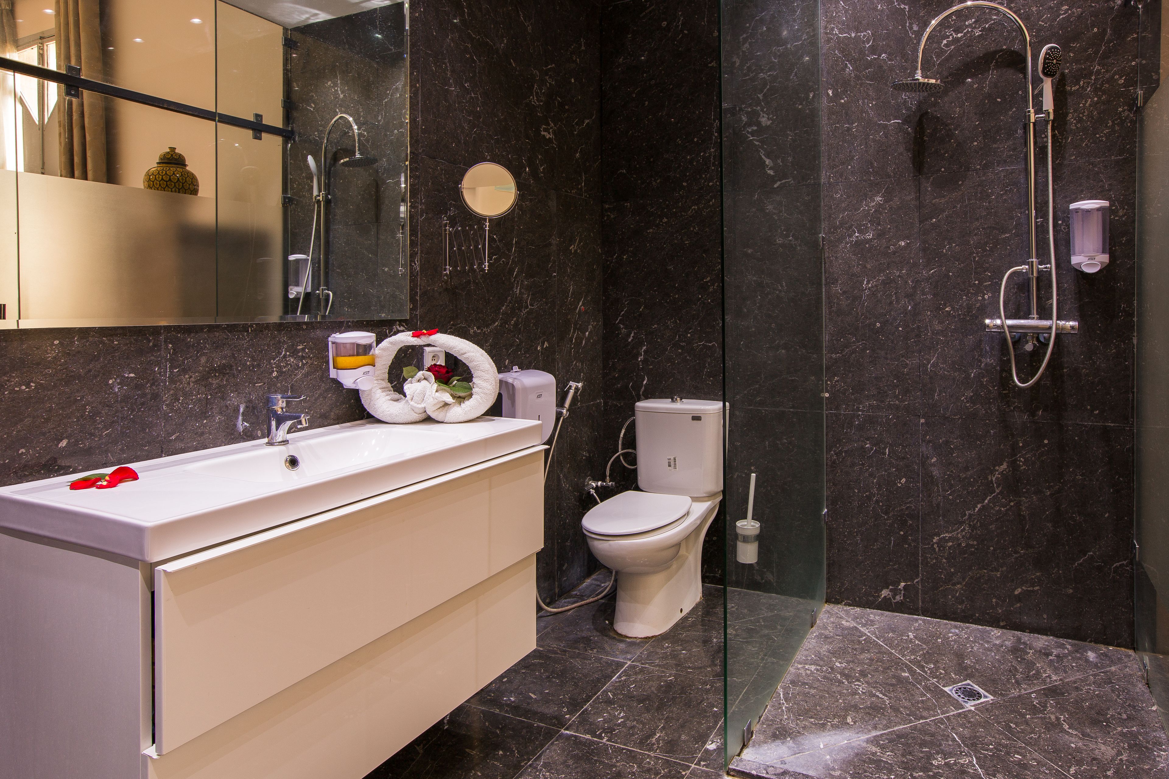 A modern bathroom with a white vanity, a toilet, and a glass shower enclosure.