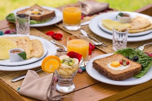 A picnic setup with various food items on plates, including toast, fruit, and a glass of orange juice.