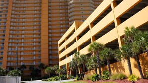 A multi-story hotel with a yellow facade, multiple balconies, and a parking structure.