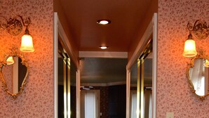 A bathroom with two sinks, a bathtub with gold fixtures, and a mirror with a floral wallpaper design.