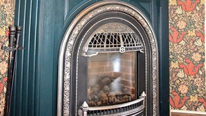 A fireplace with a decorative surround and a floral wallpaper pattern.