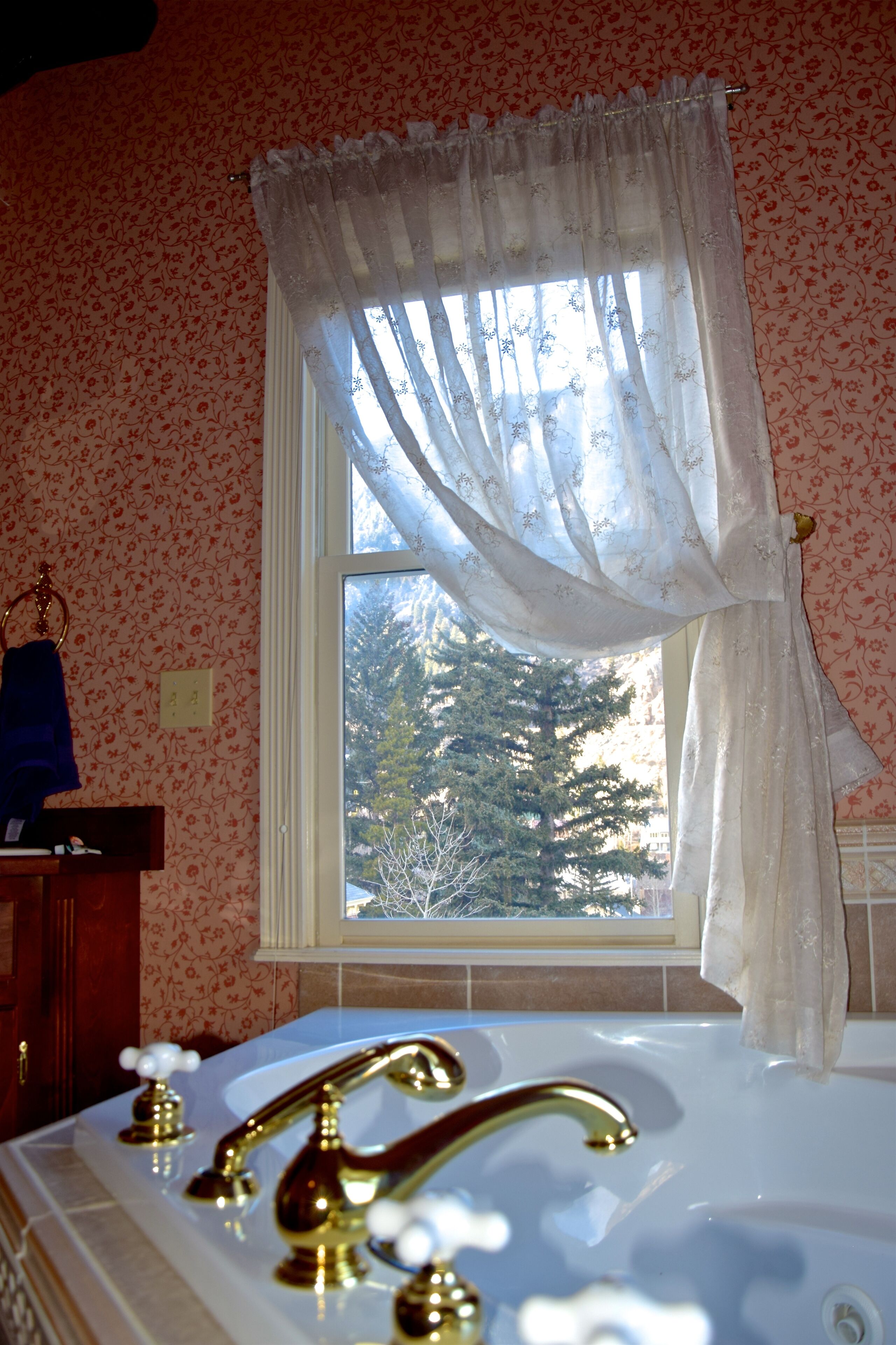 A bathroom with a bathtub, a window with a curtain, and a towel rack.