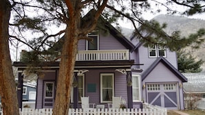 A two-story house with a white picket fence, a balcony, and a garage.