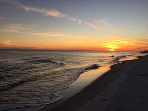 Ein Strand bei Sonnenuntergang, mit Wellen, die ans Ufer schlagen.