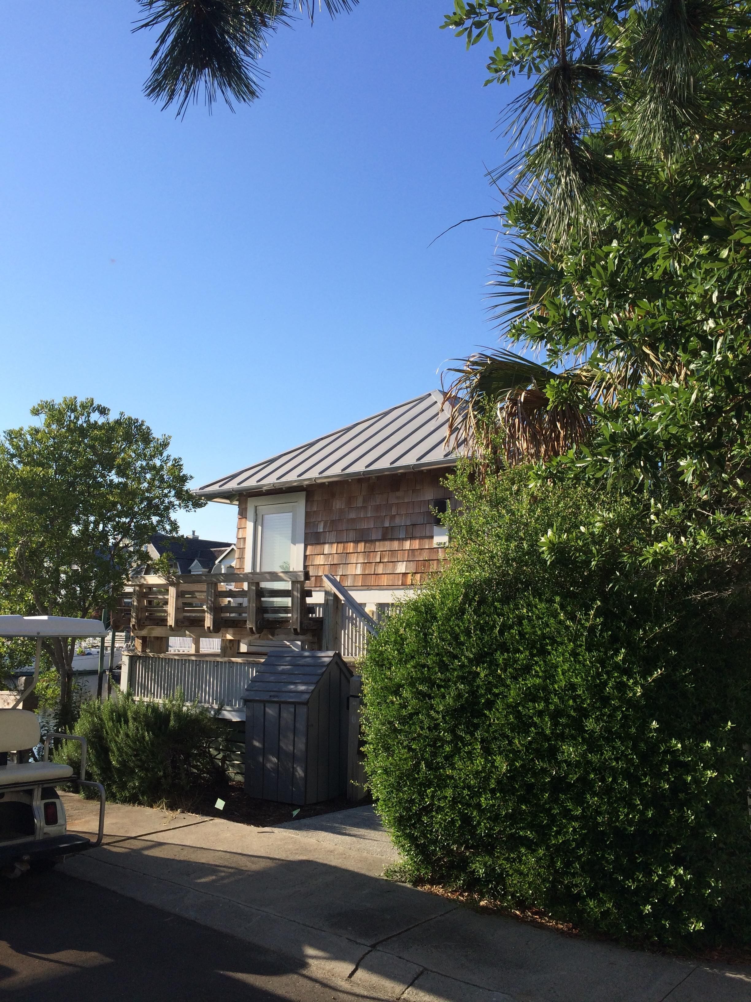 A two-story house with a metal roof, a wooden deck, and a garage.