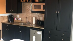 Una cocina compacta con armarios oscuros, un microondas y un refrigerador pequeño.