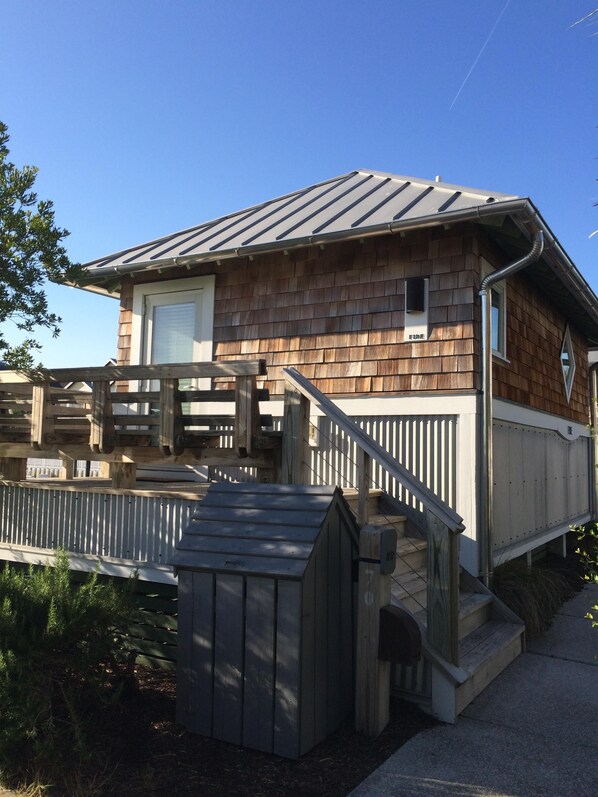A wooden house with a sloped roof, a front porch, and a small wooden shed. - Fire Hut, Bald Head Island Element/Studio On Marina (Bald Head Island)