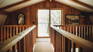 Un escalier en bois mène à une porte qui offre une vue sur les arbres et une montagne en arrière-plan.