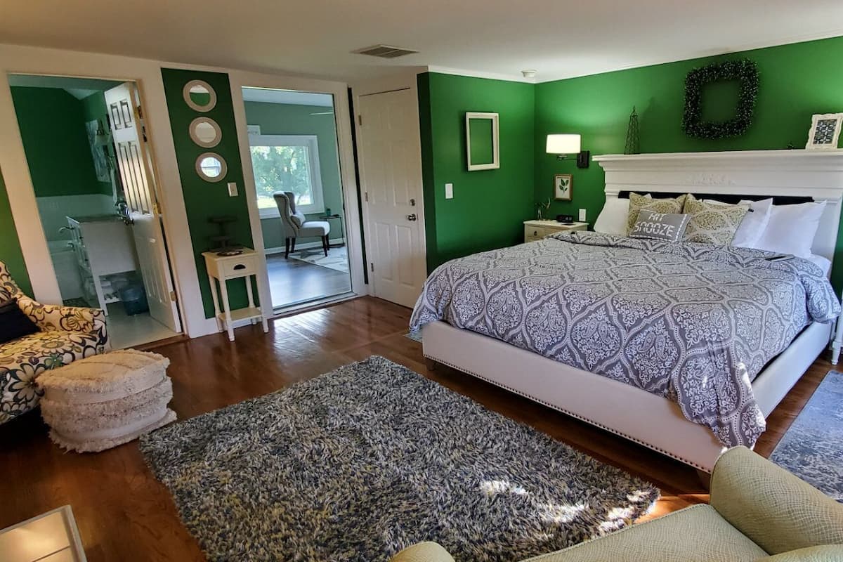 A bedroom with a bed, a chair, a nightstand, and a lamp.