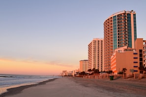 A beachfront hotel with multiple floors, a curved facade, and balconies.