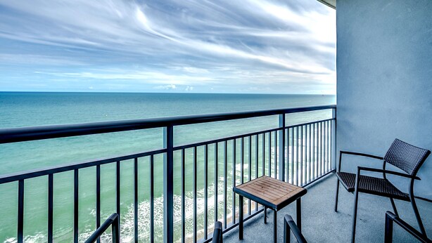 A balcony with a view of the sea, a table, and two chairs. - Fabulous Penthouse, Central MB, 2 Balconies,Watch Sunrise in Your Bed (Myrtle Beach)
