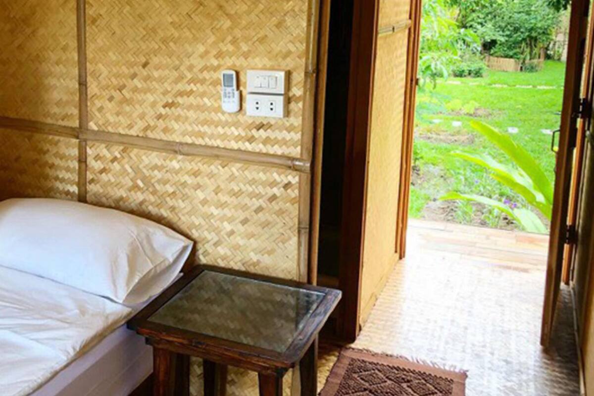 A room with a bed, a small table, and a view of a garden.