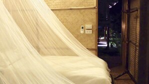 A room with a bed covered by a sheer white canopy. There is a wall socket and a door visible. - Lanna House Lanna Hut Chiangmai (San Kamphaeng)