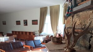 Un salon chaleureux avec une cheminée en pierre, des canapés en cuir et un coin repas.