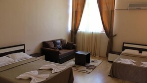 Une chambre d’hôtel avec deux lits, un canapé, une petite table et une fenêtre avec des rideaux.