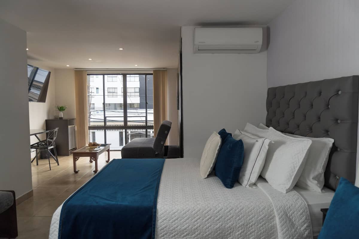 A hotel room with a large bed, a desk, a chair, and a TV.