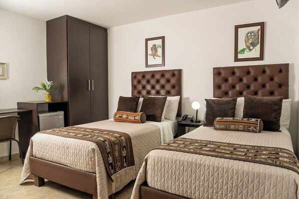 Une chambre d’hôtel avec deux lits «queen», une armoire en bois foncé et un bureau avec une chaise.