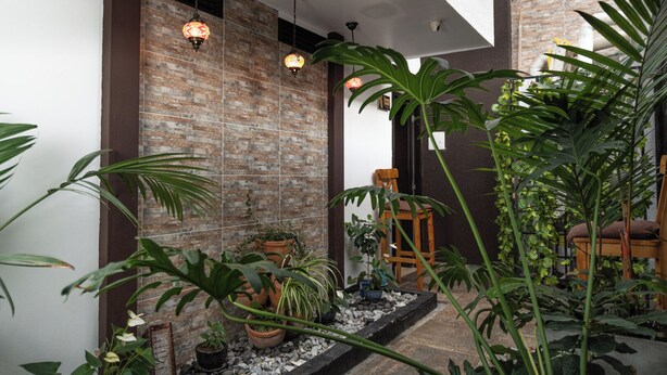 Um interior moderno com parede de tijolos, plantas em vasos e luminárias pendentes.