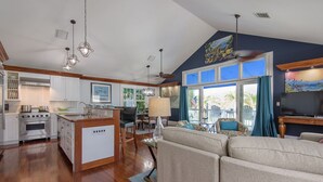A spacious living area with a large sofa, a dining table, and a kitchen with wooden cabinets and a central island.