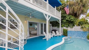 A two-story house with a swimming pool, white railings, and a flag.
