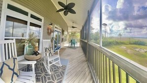A covered porch with white furniture, ceiling fans, and a view of the outdoors. - Lagoon Front, Fire Pit, Quiet, Nature ~ Otter Cove (Indian Pass)