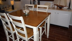 A dining area with a wooden table, white chairs, and a white cabinet with a sailboat model.