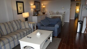 A living room with striped sofas, a white coffee table, and a dining area with a table and chairs.