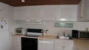 A compact kitchen with white cabinets, a stove, microwave, and dishwasher.