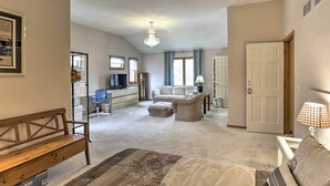 A spacious living room with a large bed, a wooden bench, a sofa, and a dining area with a table and chairs. - Eagan Home w/ Porch - 5 Mi to Mall of America! (Eagan)