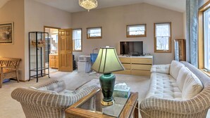 A living room with wicker furniture, a glass coffee table, a green lamp, and a television. - Eagan Home w/ Porch - 5 Mi to Mall of America! (Eagan)