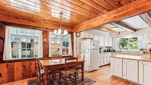 Un interior de madera con una mesa de comedor, sillas, un refrigerador y una zona de cocina.