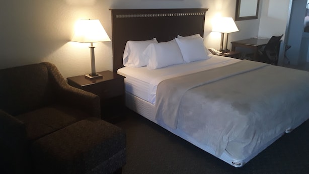 A hotel room with a bed, two bedside lamps, a chair, and a desk. - Italy Inn (Italy)