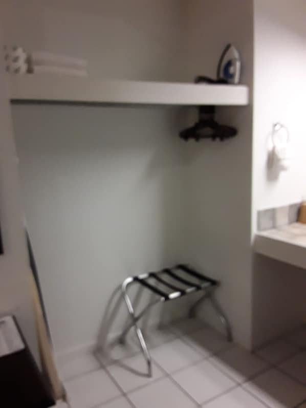 A small kitchenette with a metal drying rack, a white countertop, and a hanging clothes rack. - Italy Inn (Italy)