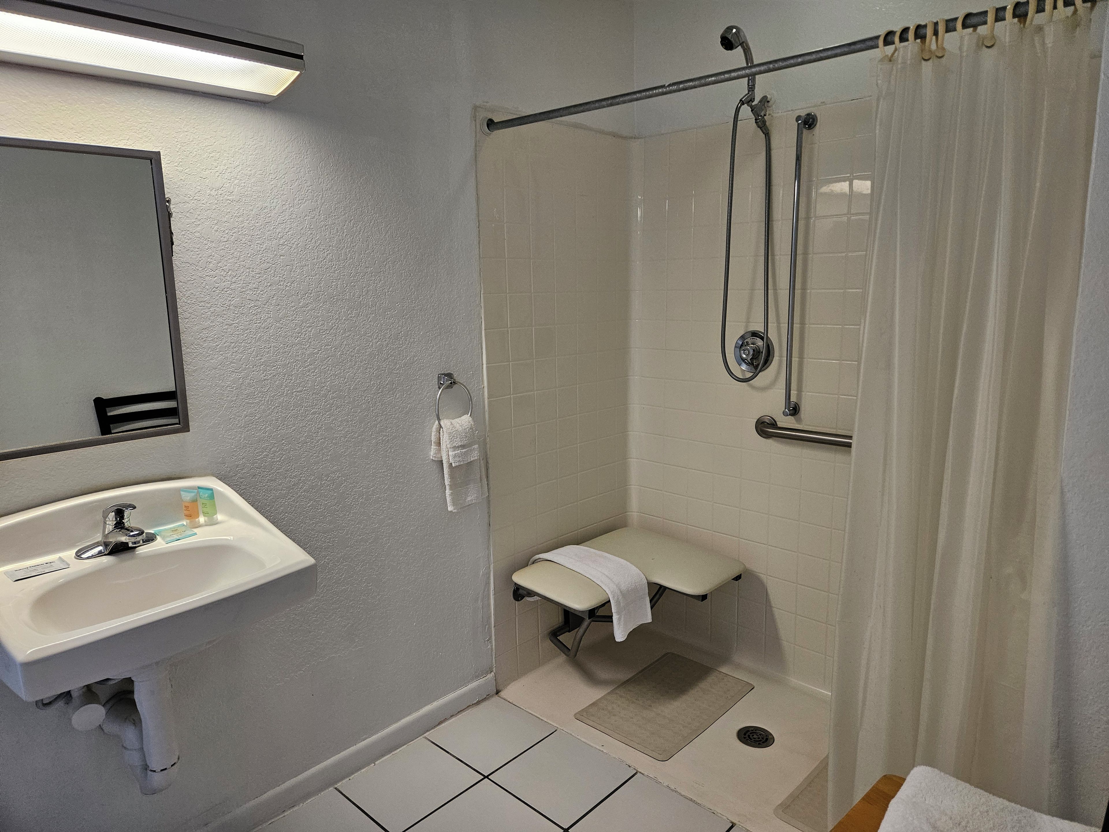 Une salle de bain équipée d’un lavabo, d’un miroir, d’une douche et de toilettes.