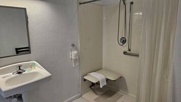 Une salle de bain équipée d’un lavabo, d’un miroir, d’une douche et de toilettes.