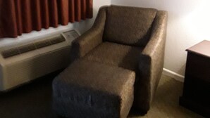 A room with a brown armchair, a small ottoman, and a heater against a wall. - Italy Inn (Italy)